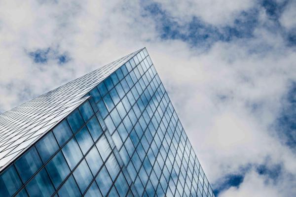 Glass building reflects a cloudy blue sky