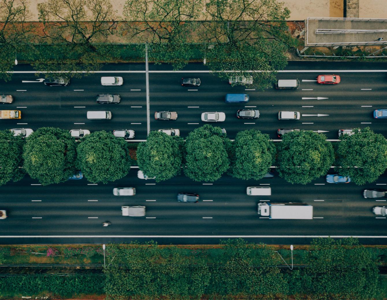 Cars moving on a two way road divided by a strip of trees in the middle