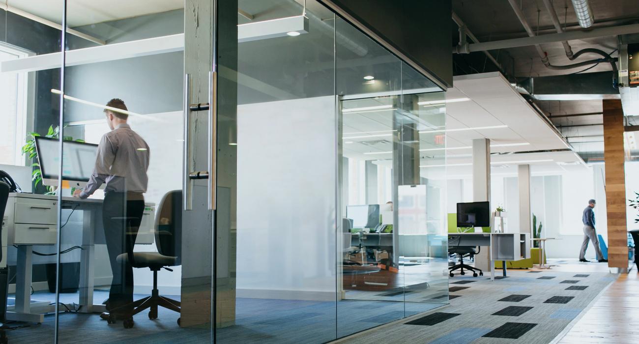Man standing in office with glass walls