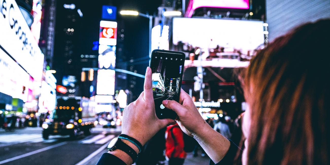 Woman taking photo with cell phone in Times Square
